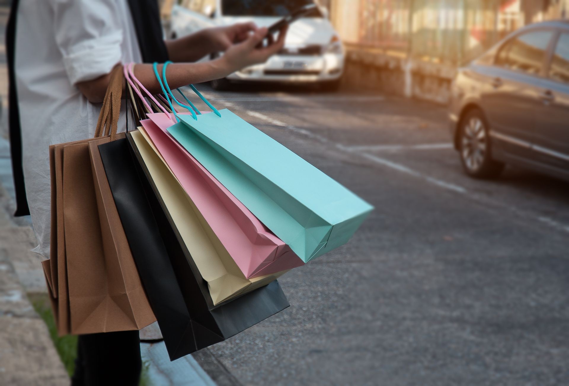In selective of the colorful shopping bags were holding by lady hand and useing mobile phone for online shopping,shopaholic , soft lgiht tone,blurry light background.